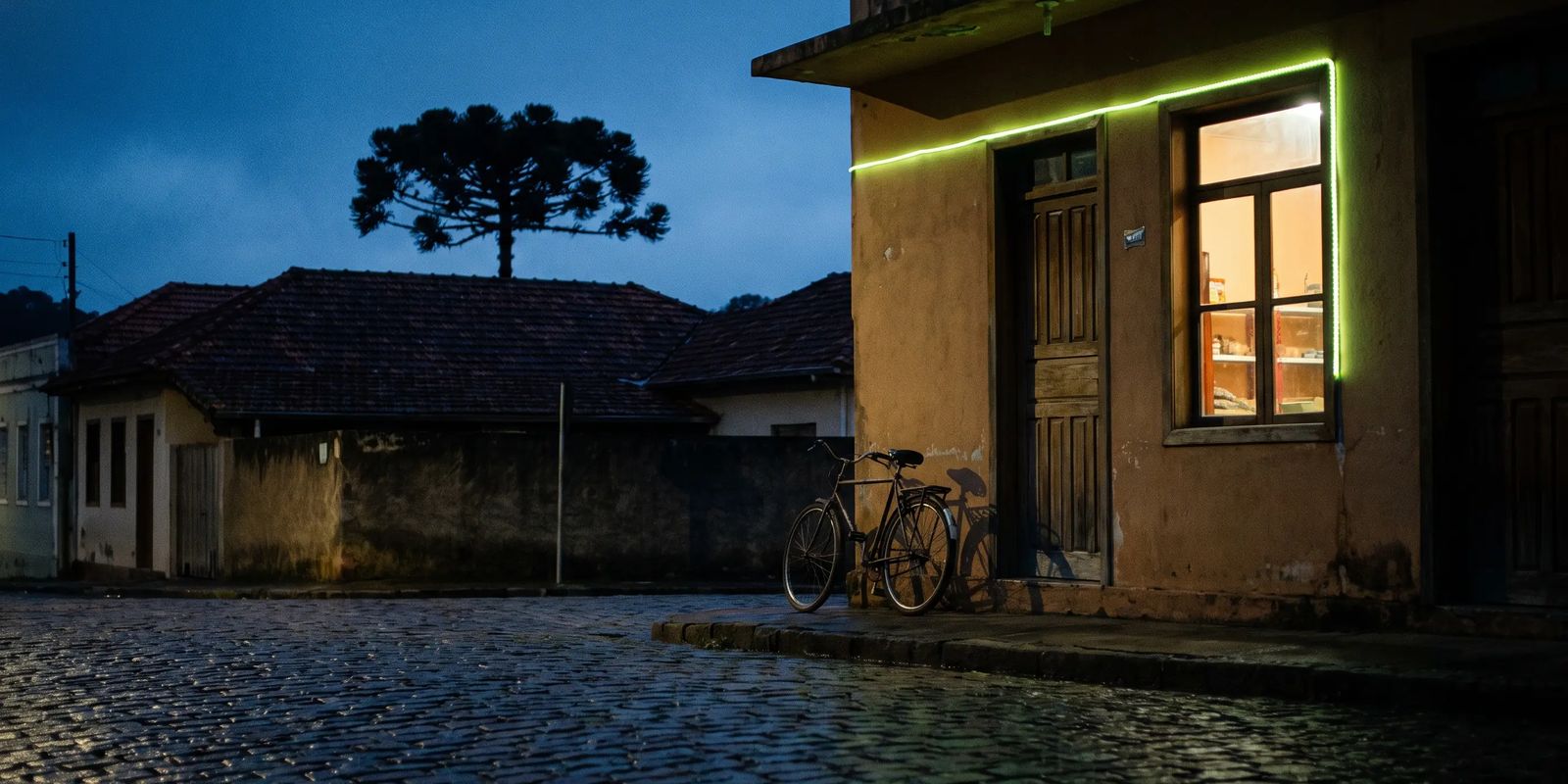 Pequena loja iluminada em rua de cidade do interior do Paraná ao anoitecer